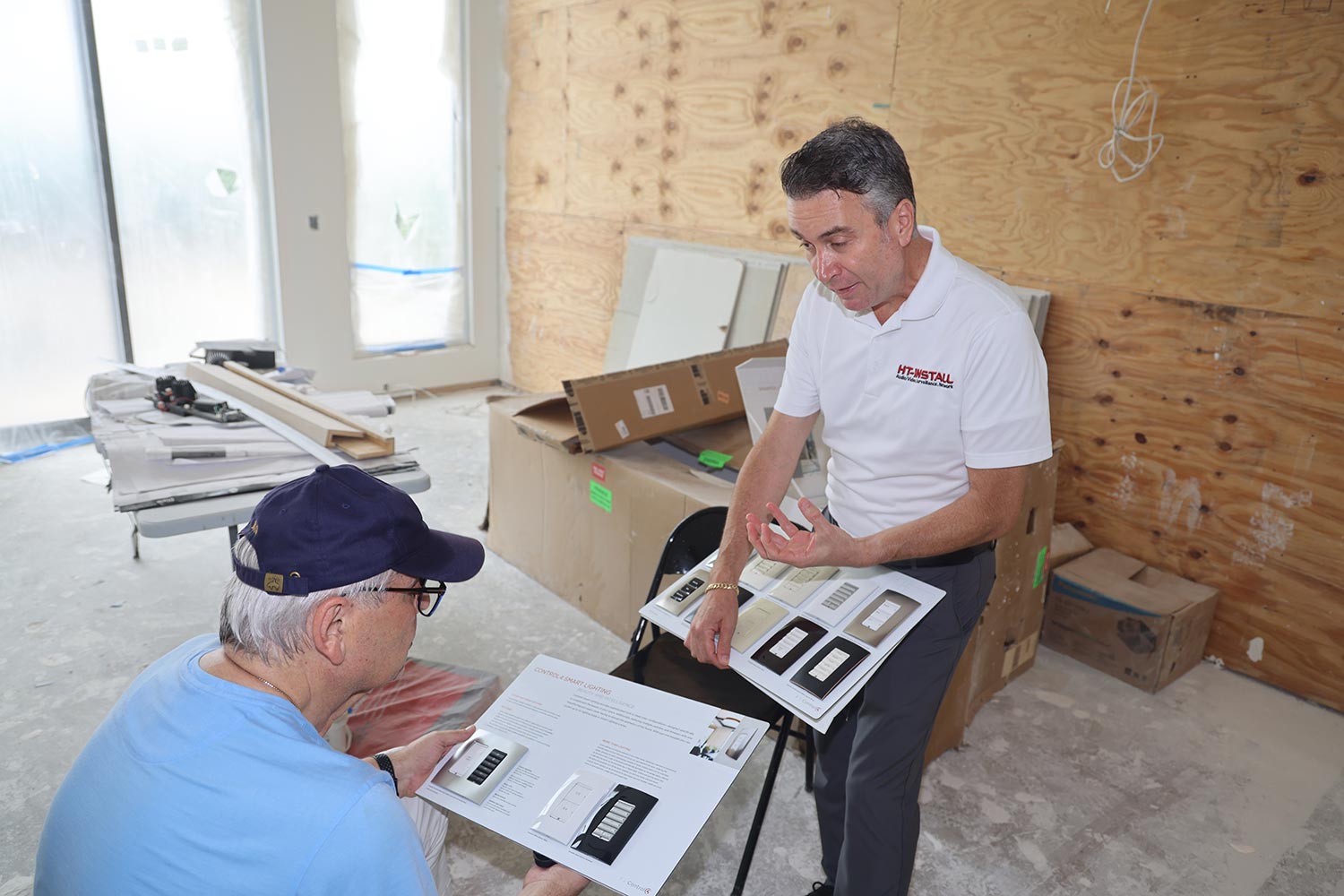 Two men reviewing smart light switch options in a partially constructed home