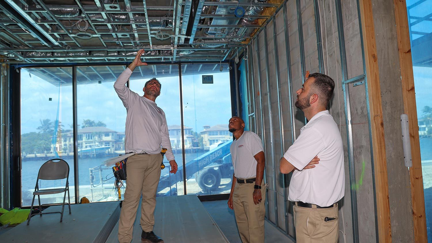 A team of three discussing the details of a construction project at a waterfront site under construction.