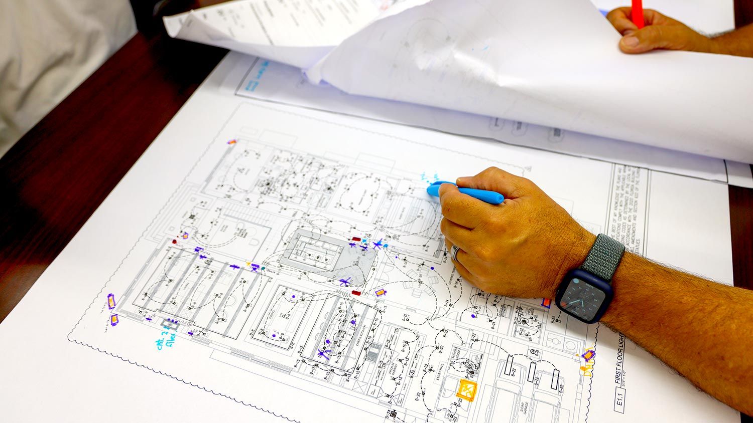 A close-up view of hands marking corrections and annotations on a blueprint.