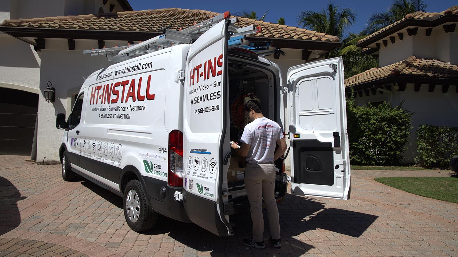 A service technician checking equipment in a van parked outside a residential home.