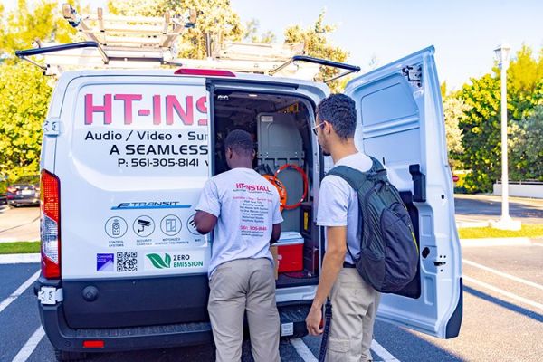 Two workers standing behind an open van, organizing equipment.