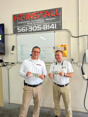 Two team members holding cash prizes, standing in front of a whiteboard in a workshop.