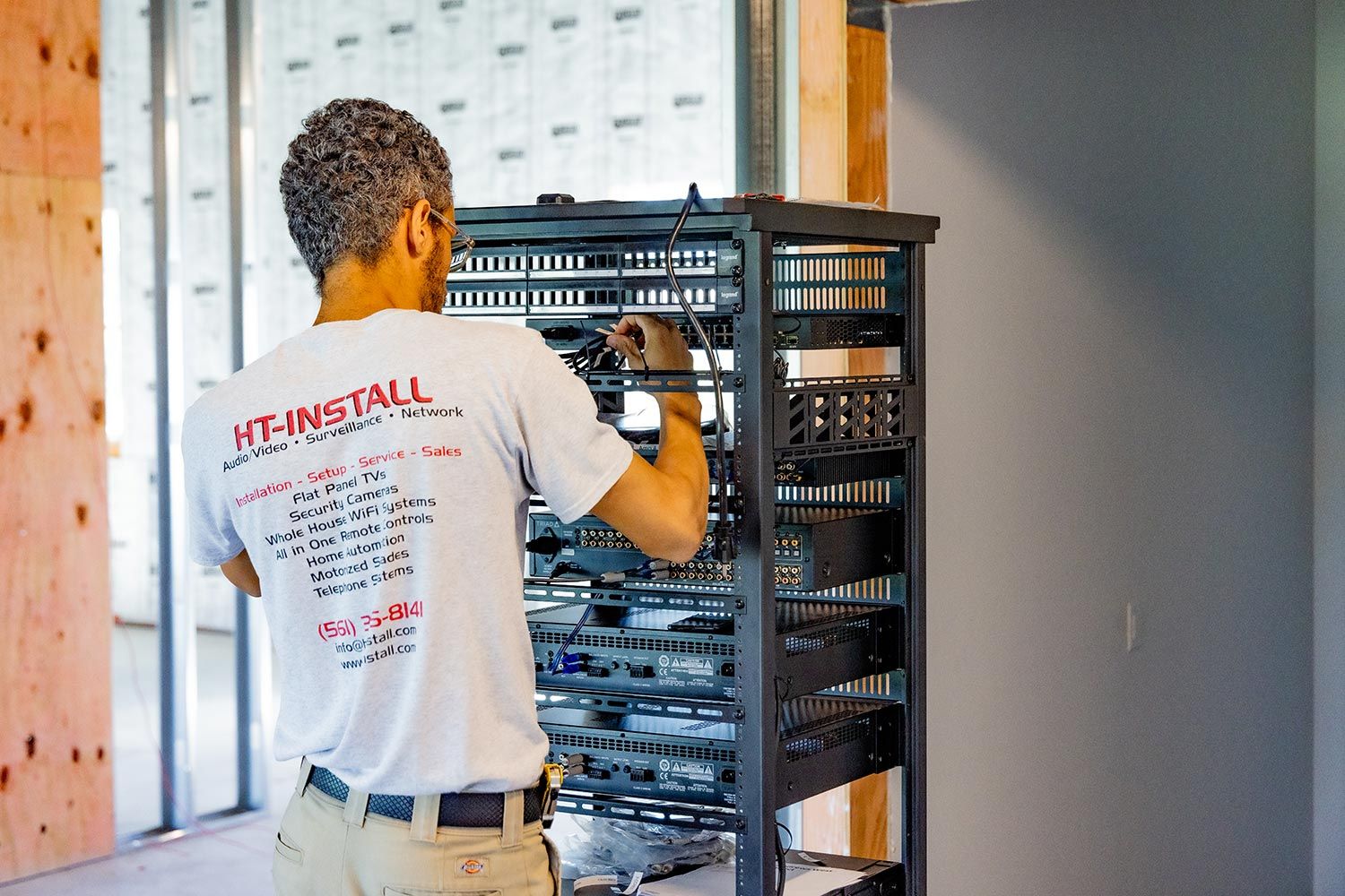 A technician working on a server rack in a partially constructed space.