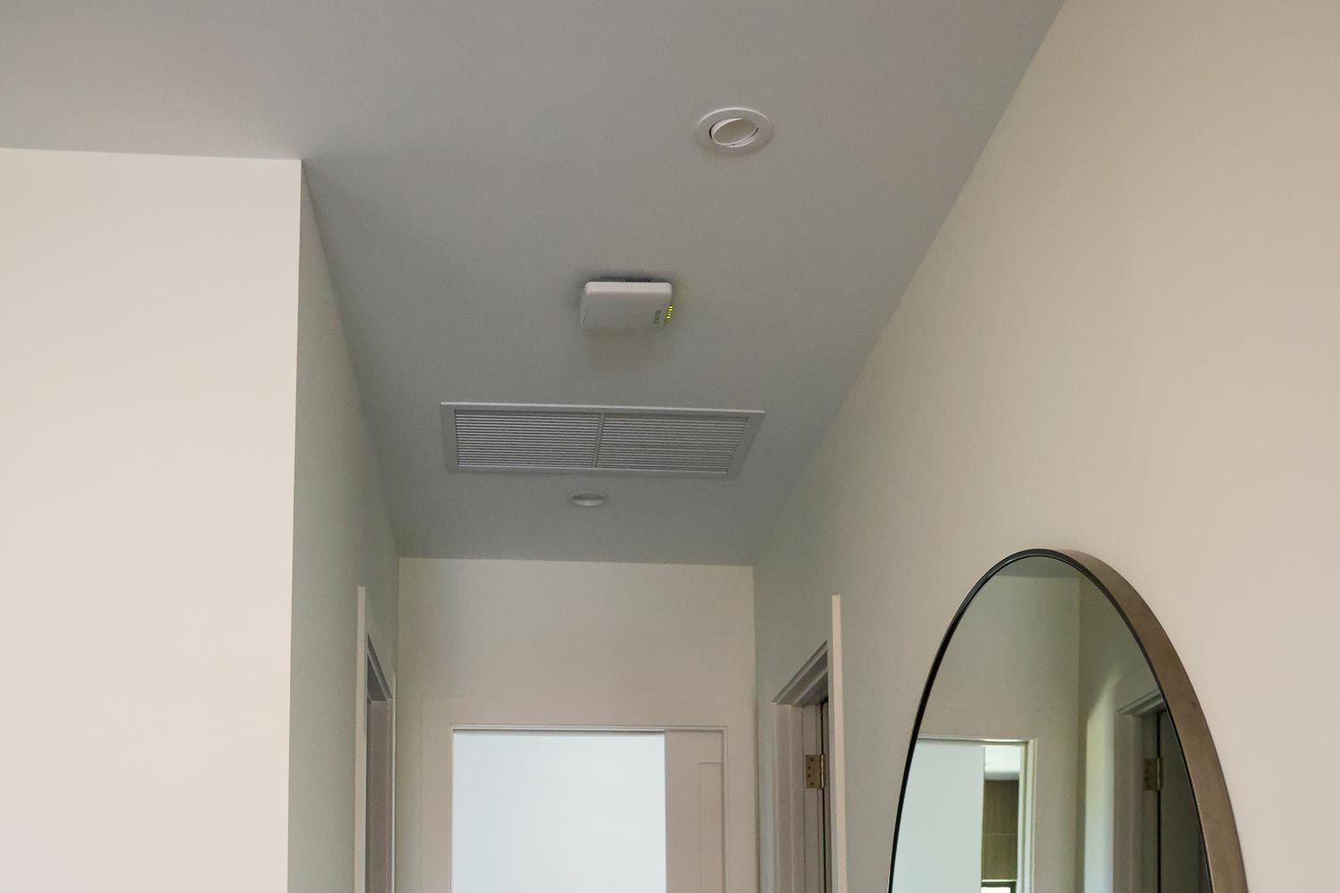 Ceiling-mounted networking hardware and an air vent in a modern hallway.