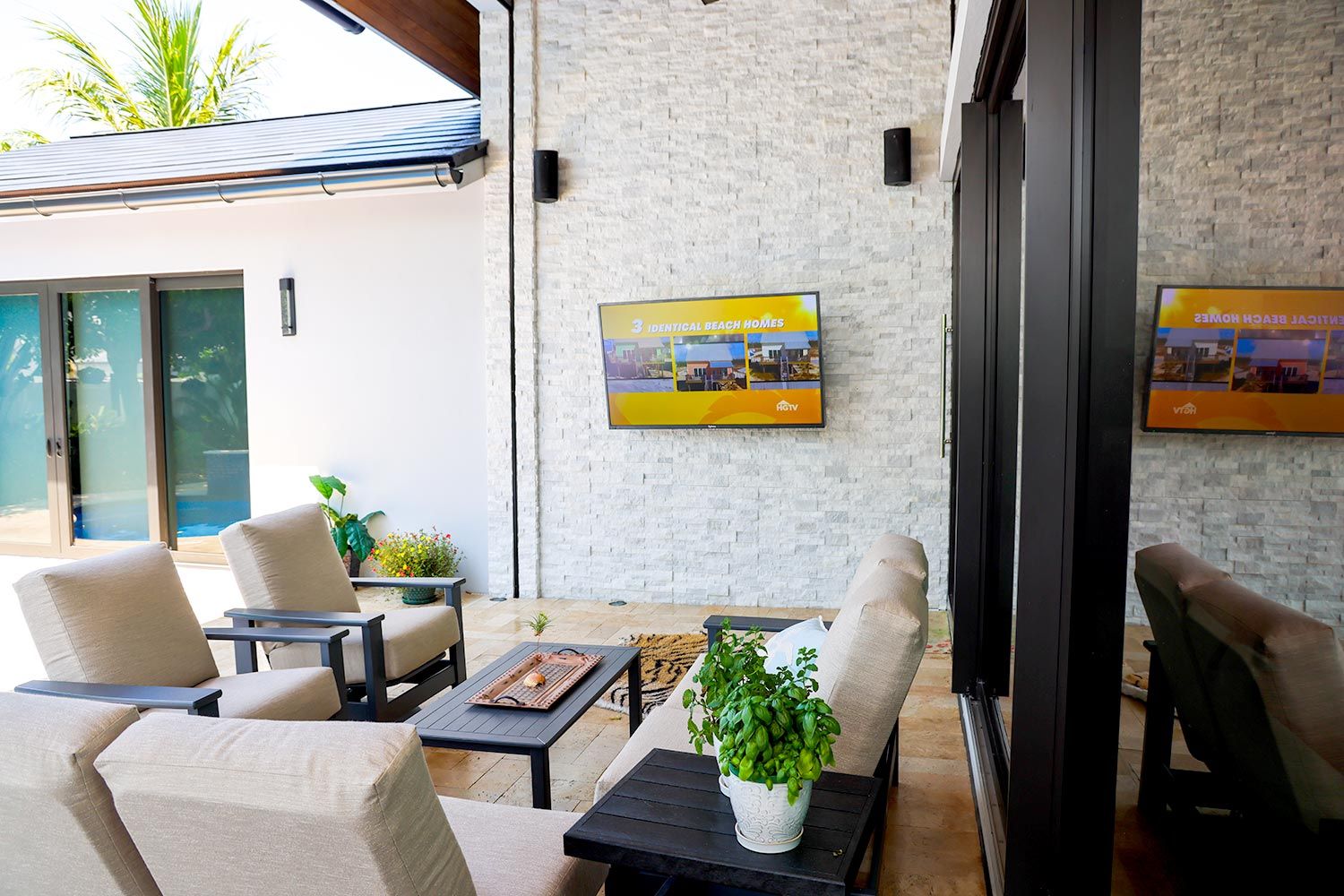 An outdoor living area with comfortable seating and a wall-mounted TV.