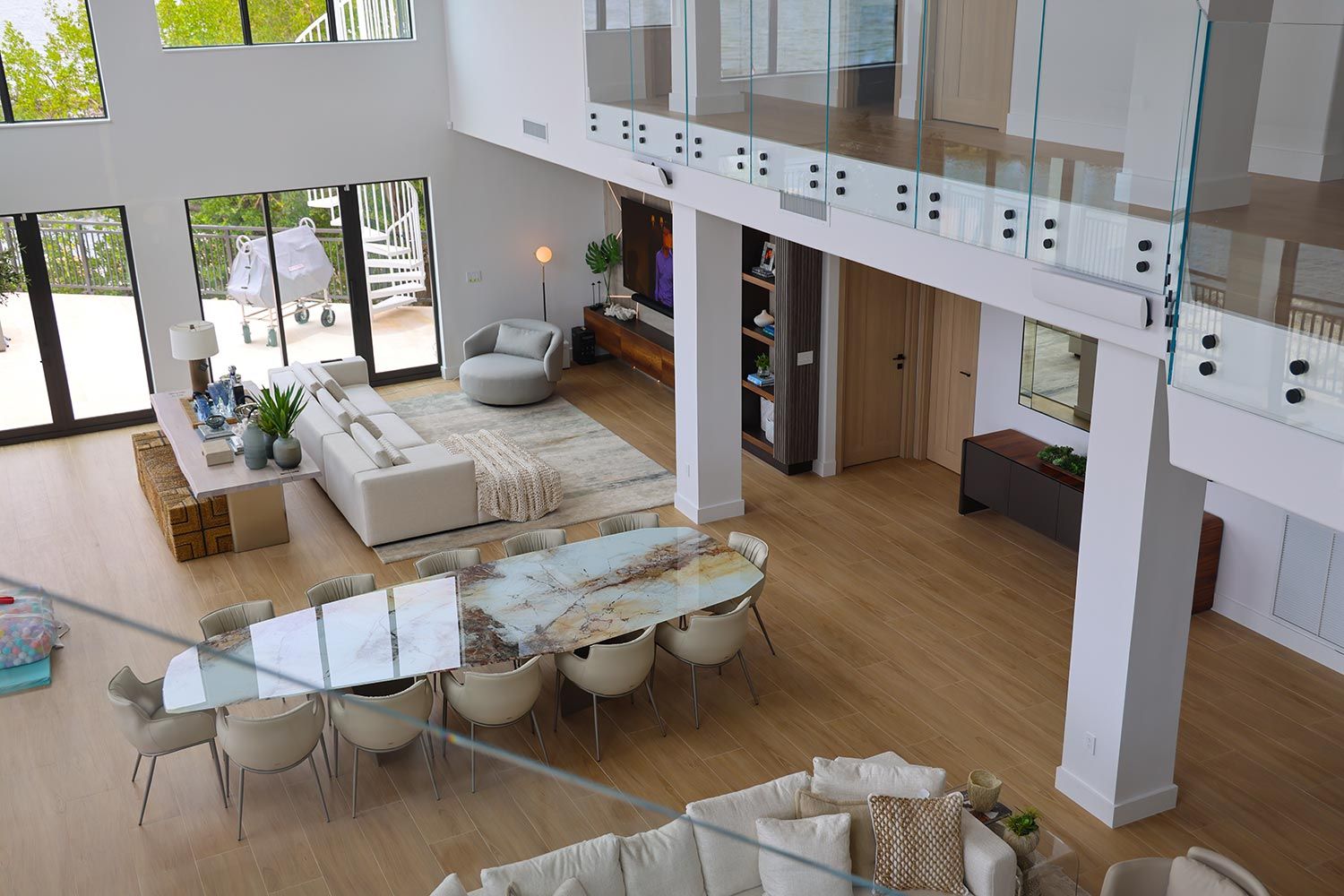 A spacious modern living room with a marble dining table, a cozy seating area, and large glass doors opening to an outdoor space.