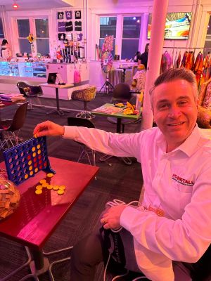 A man smiling while playing a game of Connect Four in a brightly lit recreational space.